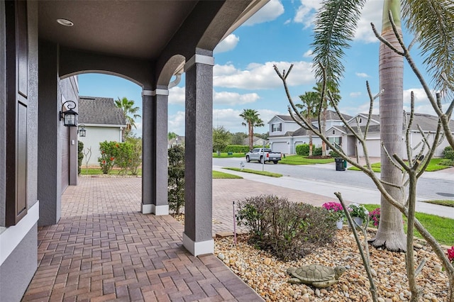 view of patio / terrace featuring covered porch, a residential view, and decorative driveway