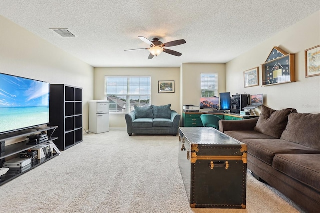 living area featuring a textured ceiling, carpet, visible vents, and a ceiling fan