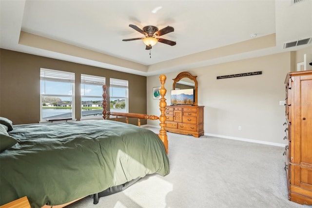 bedroom featuring ceiling fan, visible vents, baseboards, carpet, and a raised ceiling