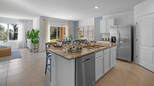 kitchen featuring stone counters, plenty of natural light, stainless steel appliances, and a sink