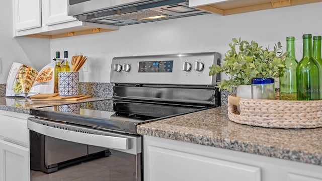 kitchen with tile patterned flooring, light stone countertops, stainless steel range with electric stovetop, and white cabinetry