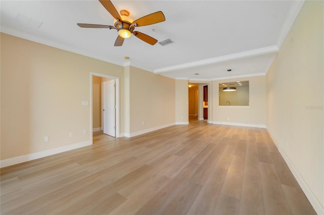 empty room featuring visible vents, ornamental molding, ceiling fan, light wood-type flooring, and baseboards