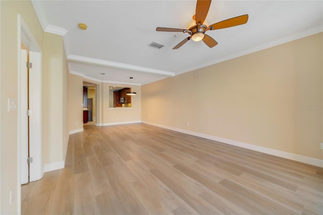 spare room featuring ornamental molding, light wood-type flooring, visible vents, and baseboards