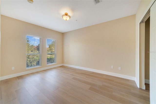 empty room featuring light wood-type flooring, visible vents, and baseboards