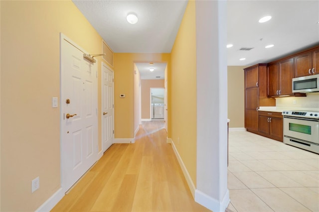 hallway with recessed lighting, visible vents, baseboards, and light tile patterned flooring