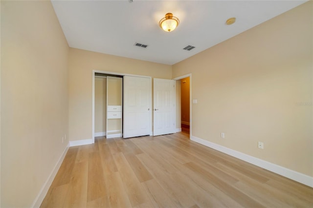 unfurnished bedroom featuring light wood-style flooring, a closet, visible vents, and baseboards