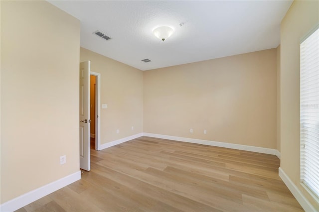 spare room featuring light wood finished floors, baseboards, and visible vents