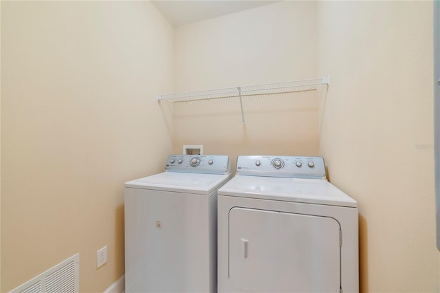 washroom with laundry area, visible vents, and washer and clothes dryer