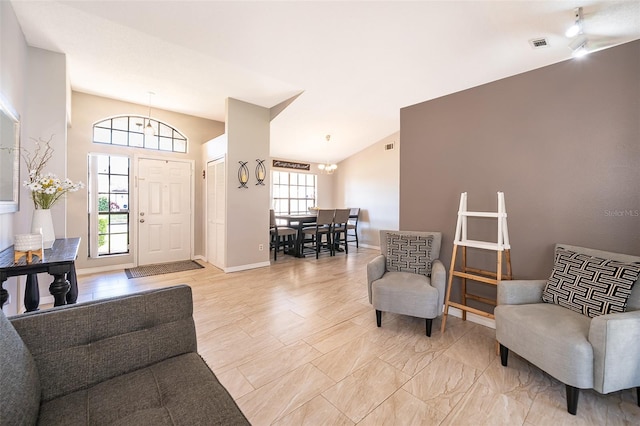 foyer entrance featuring a chandelier, lofted ceiling, visible vents, and baseboards