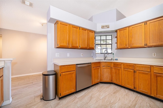 kitchen with light countertops, visible vents, stainless steel dishwasher, brown cabinetry, and a sink