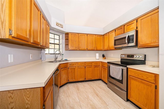 kitchen with light countertops, appliances with stainless steel finishes, brown cabinetry, and a sink