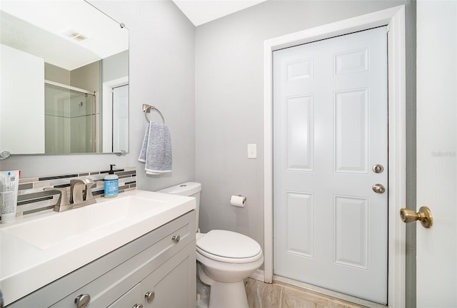 full bath with visible vents, toilet, a shower with shower door, vanity, and backsplash