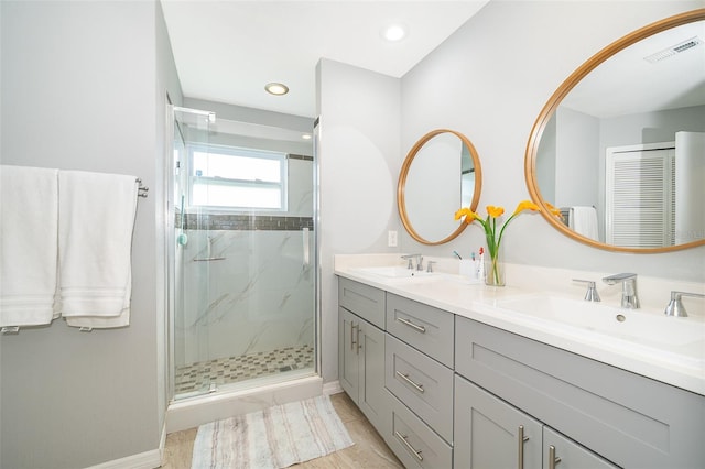 bathroom featuring visible vents, a sink, a marble finish shower, and double vanity