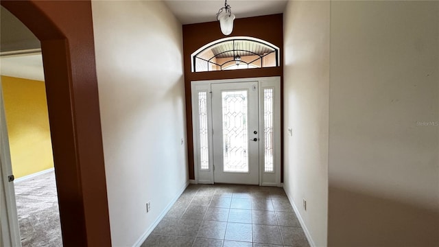 tiled foyer with arched walkways and baseboards