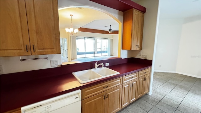 kitchen featuring arched walkways, light tile patterned floors, dark countertops, a sink, and dishwasher