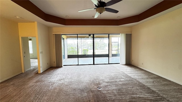 empty room with carpet, a raised ceiling, a healthy amount of sunlight, and baseboards