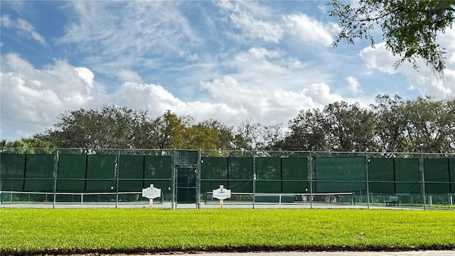 view of sport court featuring fence and a lawn