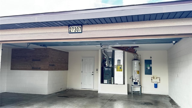 garage with concrete block wall, electric panel, and water heater