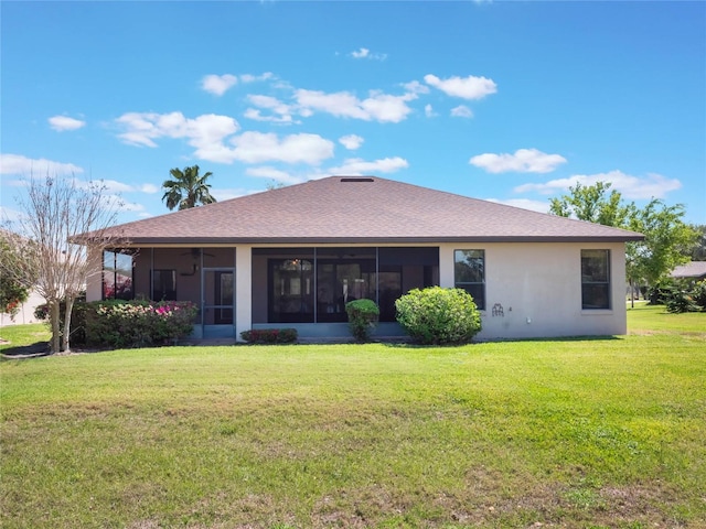 back of house with roof with shingles, a yard, a sunroom, and stucco siding