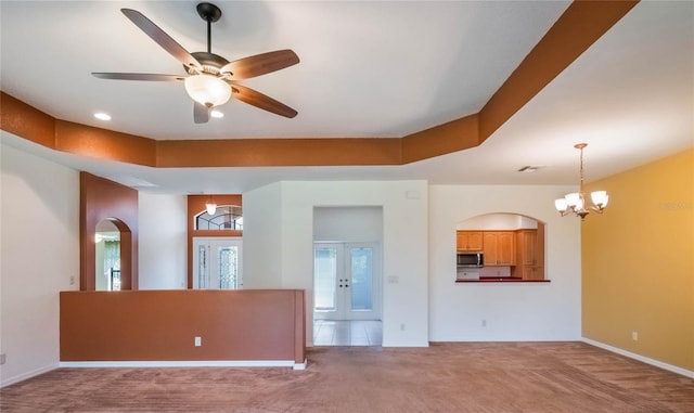 27307 Pine Straw Rd, Leesburg, FL 34748 - unfurnished living room featuring arched walkways, ceiling fan with notable chandelier, a raised ceiling, and carpet floors