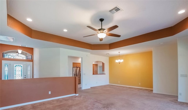 27307 Pine Straw Rd, Leesburg, FL 34748 - empty room with light carpet, visible vents, ceiling fan with notable chandelier, and a raised ceiling