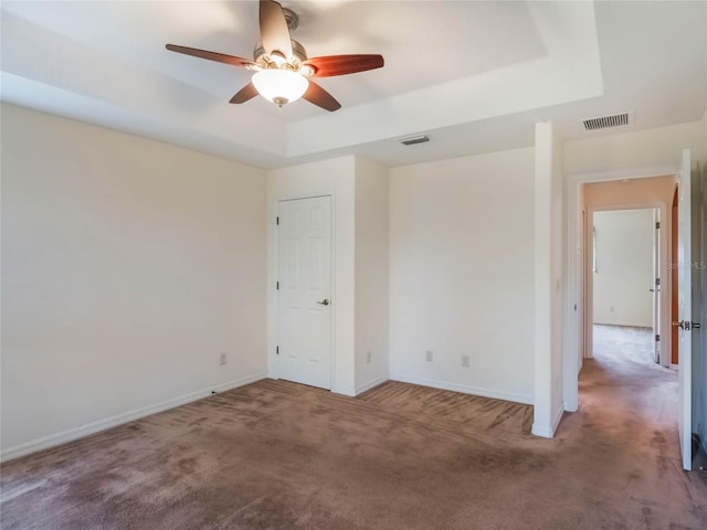 27307 Pine Straw Rd, Leesburg, FL 34748 - empty room featuring a tray ceiling, carpet, visible vents, and baseboards