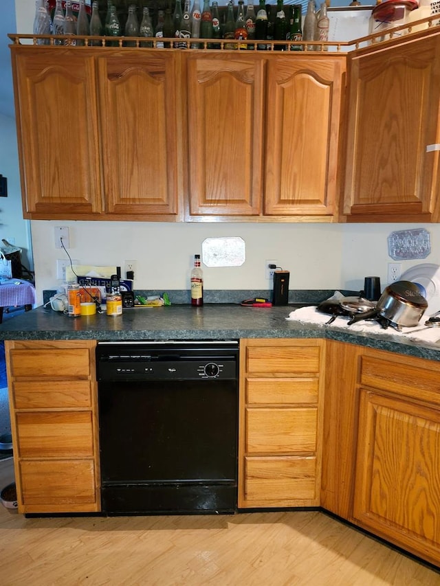 kitchen with dark countertops, light wood-type flooring, brown cabinetry, and dishwasher