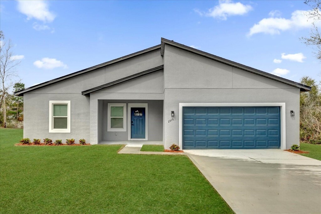 view of front of property featuring a front yard, an attached garage, concrete driveway, and stucco siding