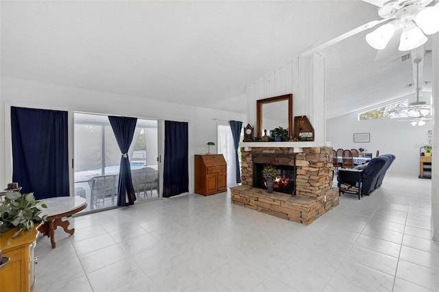 living area with vaulted ceiling, a stone fireplace, and ceiling fan