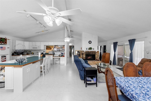 interior space featuring lofted ceiling, ceiling fan, a fireplace, and track lighting