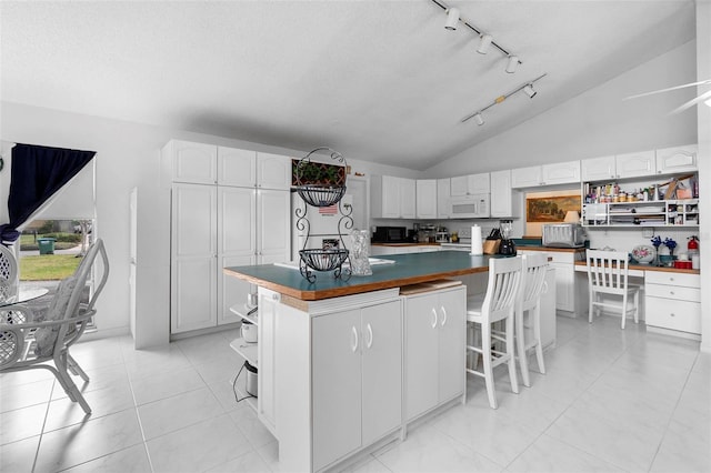 kitchen featuring dark countertops, a center island, open shelves, and white microwave