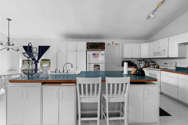 kitchen with white appliances, dark countertops, vaulted ceiling, white cabinetry, and a sink