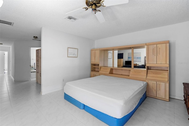 bedroom with a ceiling fan, visible vents, a textured ceiling, and baseboards