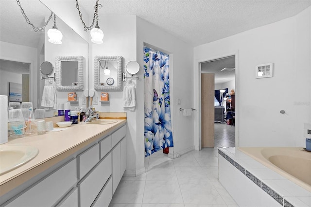 ensuite bathroom featuring double vanity, tiled bath, ensuite bathroom, a sink, and a textured ceiling