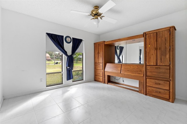 unfurnished bedroom featuring a ceiling fan, a textured ceiling, and baseboards