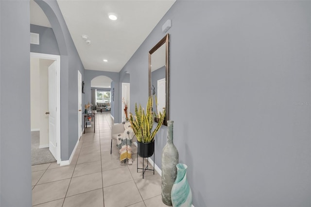 hall with arched walkways, light tile patterned floors, recessed lighting, and baseboards