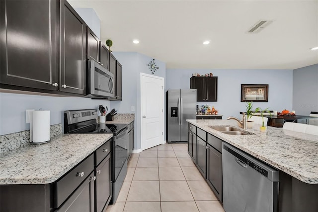 kitchen with light tile patterned floors, a sink, visible vents, appliances with stainless steel finishes, and an island with sink