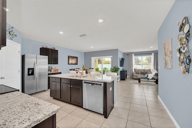 kitchen with light tile patterned floors, stainless steel appliances, visible vents, open floor plan, and a sink