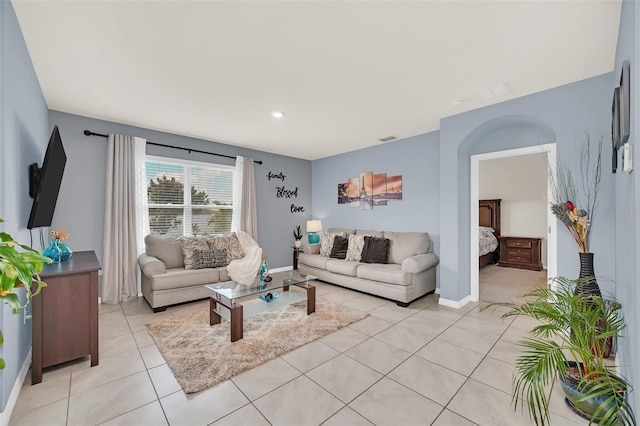 living area with arched walkways, visible vents, baseboards, and light tile patterned floors