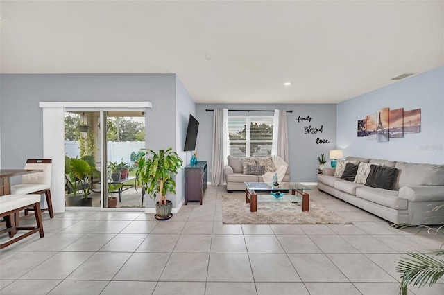 living room featuring light tile patterned flooring, visible vents, and baseboards