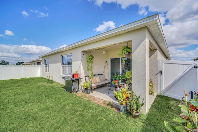 back of house featuring a patio, stucco siding, a lawn, a gate, and fence