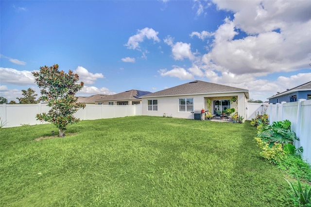 back of property featuring stucco siding, a fenced backyard, a lawn, and a patio