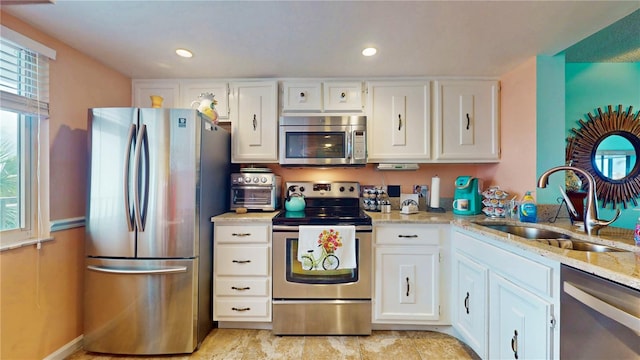 kitchen featuring stainless steel appliances, white cabinetry, and a sink