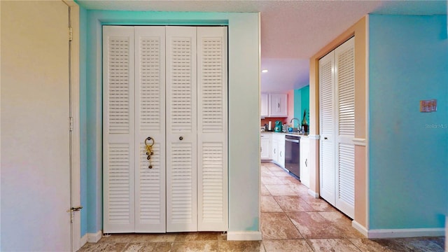 corridor featuring a sink, baseboards, and a textured ceiling