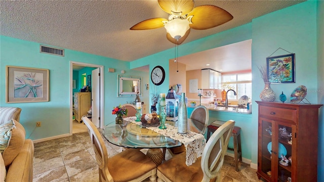 dining room with visible vents, ceiling fan, a textured ceiling, and baseboards