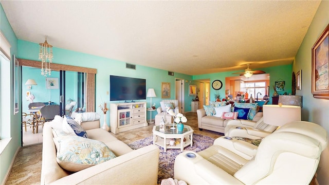 living room featuring a textured ceiling, ceiling fan, visible vents, and baseboards