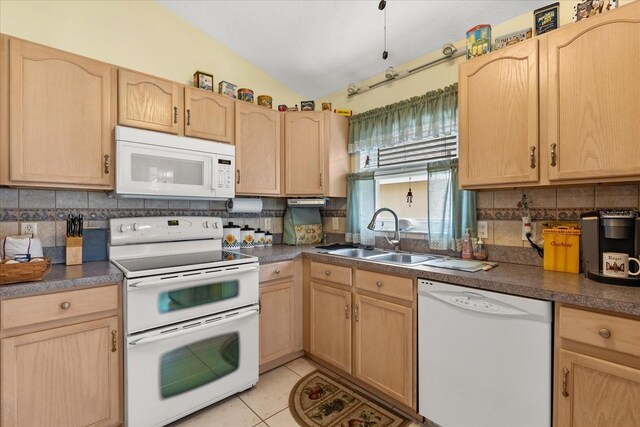 kitchen featuring light tile patterned floors, light brown cabinetry, white appliances, and a sink