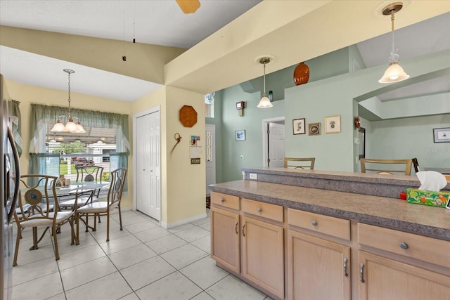 kitchen featuring light tile patterned flooring, decorative light fixtures, dark countertops, and light brown cabinetry