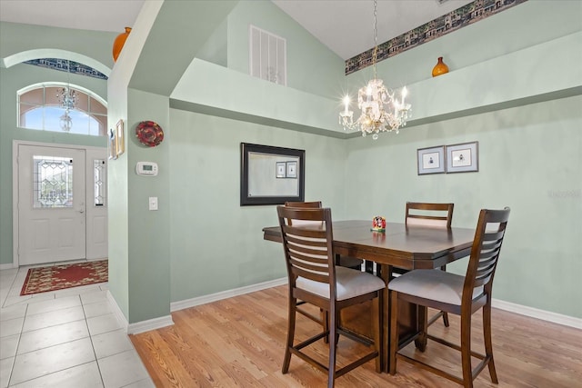 dining area featuring light wood finished floors, visible vents, and a notable chandelier