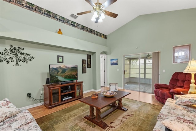 living room featuring baseboards, visible vents, arched walkways, and wood finished floors